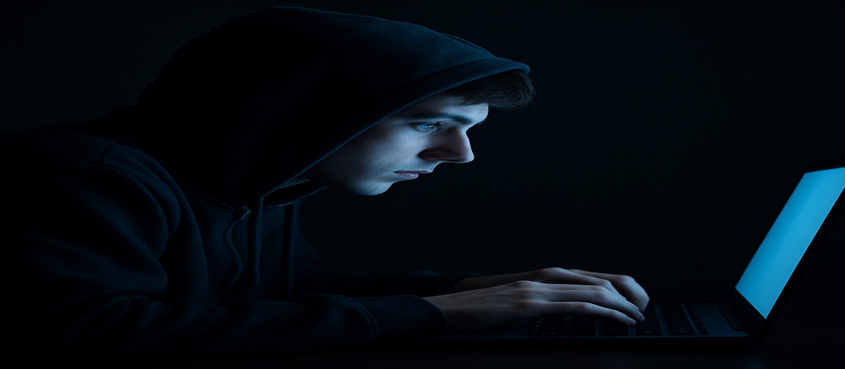 একজন ব্যক্তি অন্ধকারে ল্যাপটপে বসে একাগ্র দৃষ্টিতে qqgg ওয়েবসাইটে অনলাইন গেম খেলছেন